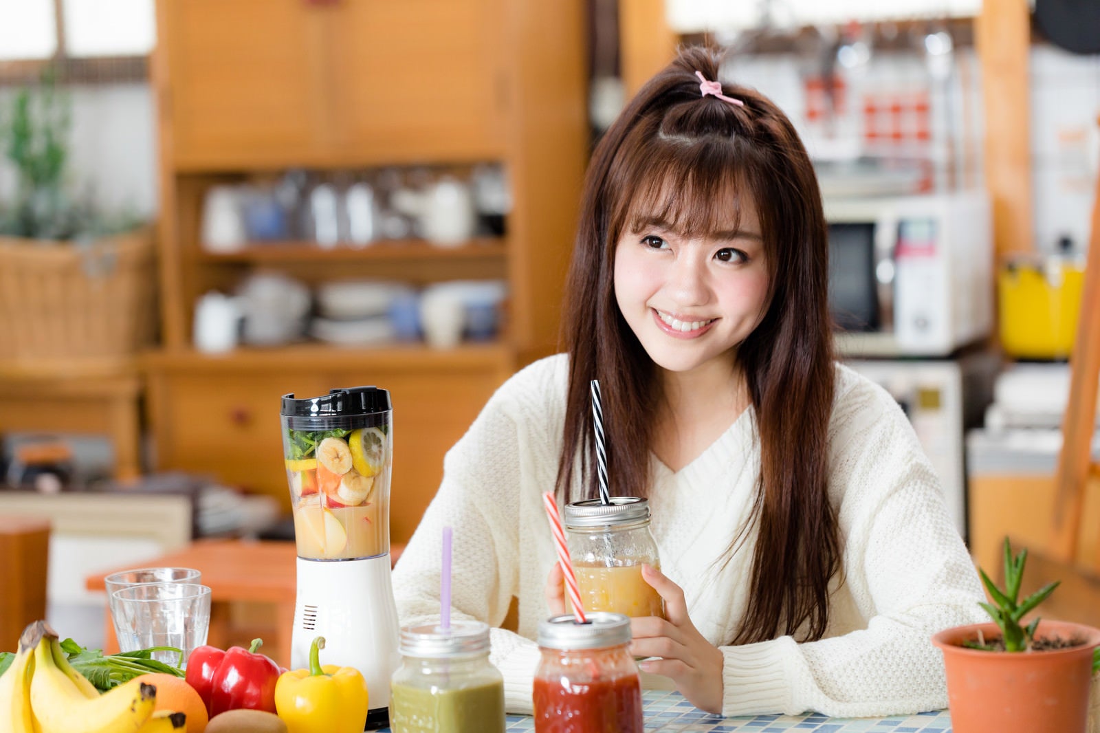 「台所でスムージーを飲む女性」の写真［モデル：河村友歌］